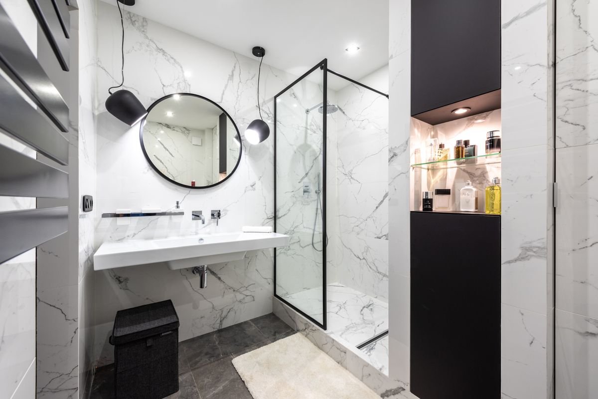Black and White Marble Bathroom with Round Mirror and Glass Shower