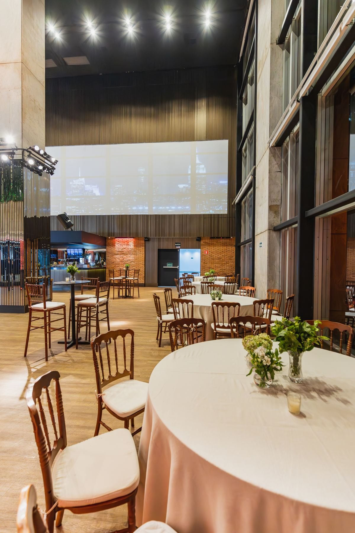 Modern Event Hall with Blush Tablecloths and Skyline Projection