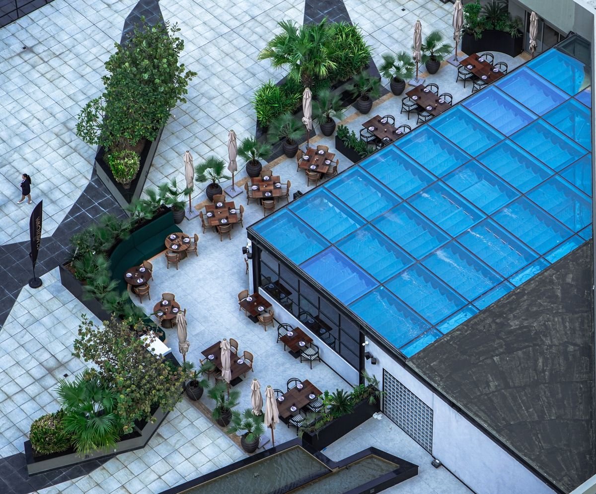 Aerial View of Glass-Covered Rooftop Pool Terrace with Palms