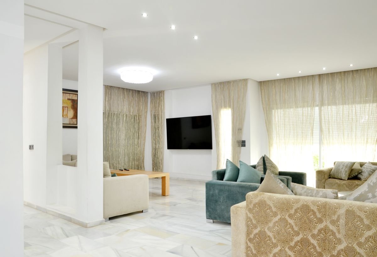 Bright living room with sheer curtains, marble floor and plush seating