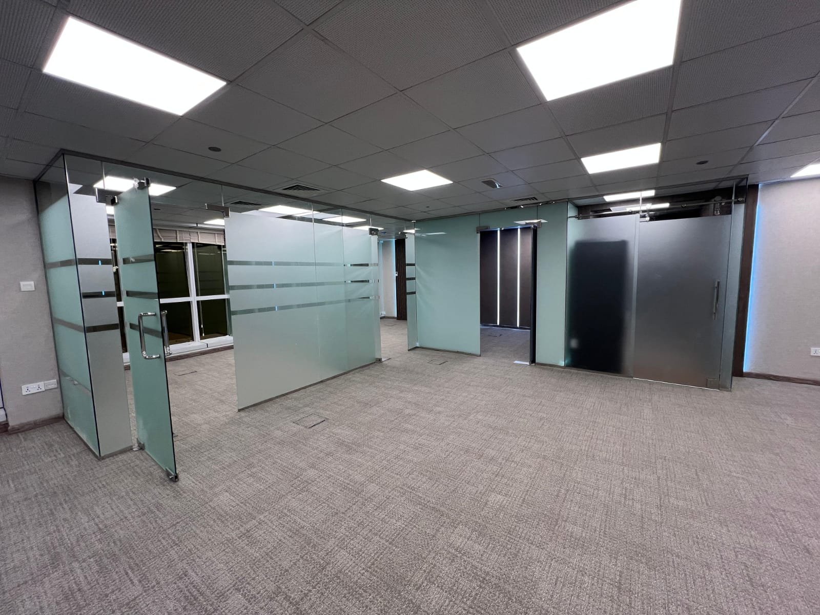 Open Office Layout with Glass Partitions and Carpet Flooring